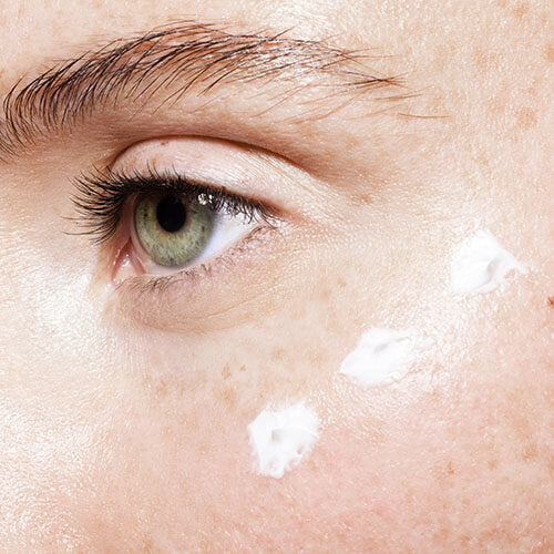 Skincare on a woman's cheek possibly to prevent premature aging