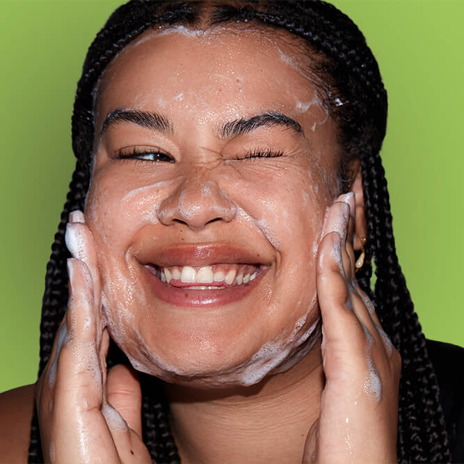 A woman washing her face, one of Dr. Pimple Popper's New Year's Skincare resolutions