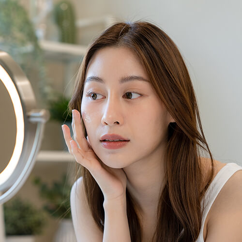 A woman layering on skincare for dry or dull skin
