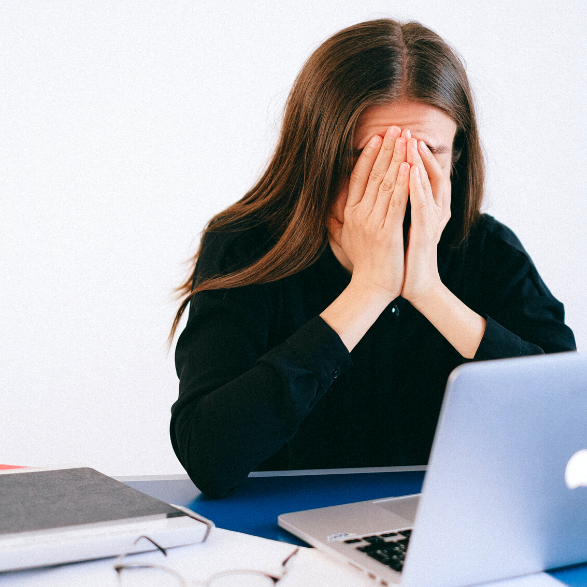 a woman at a computer stressed out, which can impact her skin health