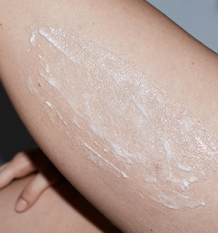 A woman using SLMD by Dr. Pimple Popper Glycolic Acid Body Scrub for dry rough body skin and keratosis pilaris