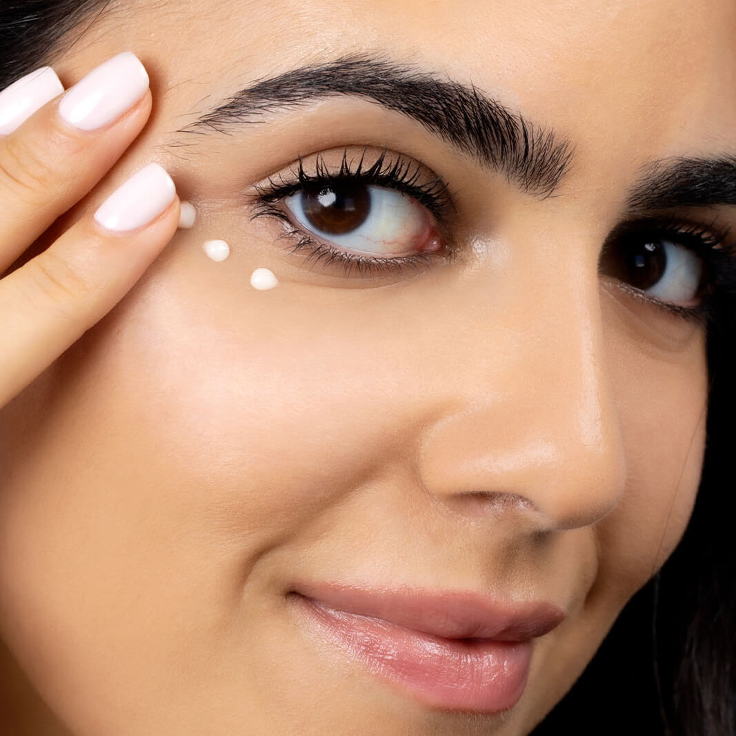 Woman putting on Night Light Retinol Eye Cream by SLMD Skincare