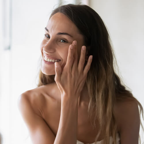 A woman applying skincare to prevent visible signs of aging