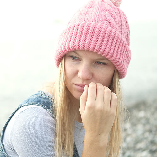 A woman in a pink hat thinking contemplating her wintertime acne breakouts