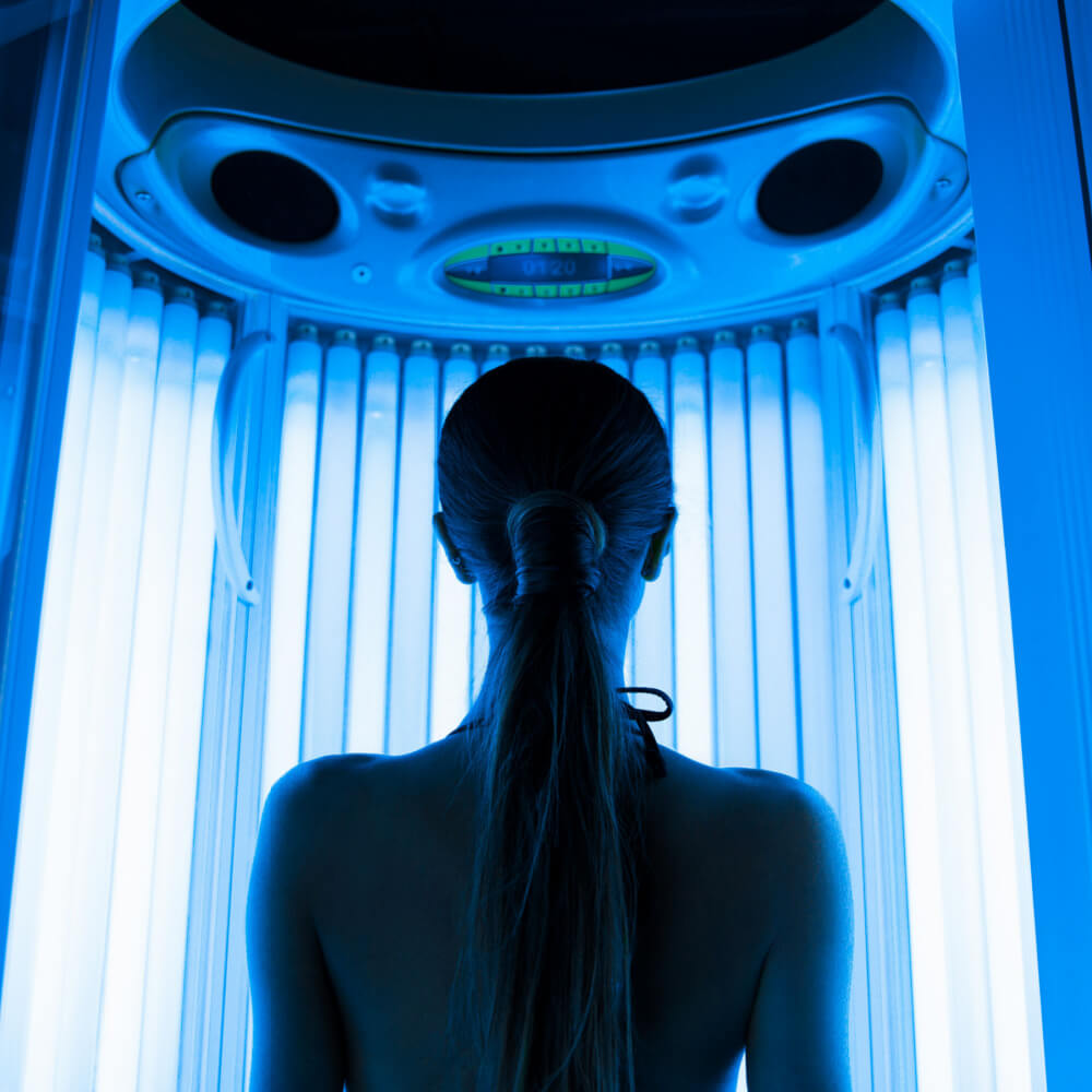 A woman in a tanning salon getting exposed to high dose UV radiation