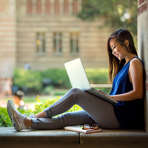A college student with glowing skin working on her laptop