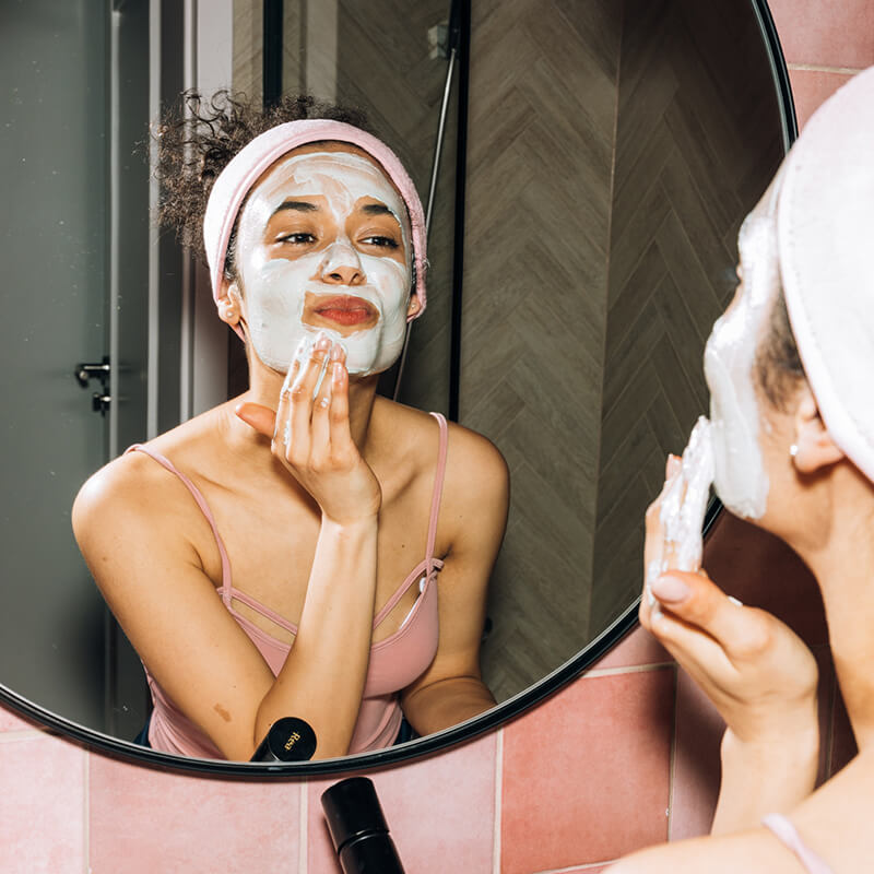 Woman applying a face mask treatment that can be a part of Dr. Pimple Popper's Skincare Philosophy