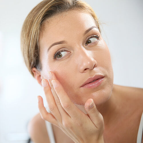 A woman layering skincare for aging skin