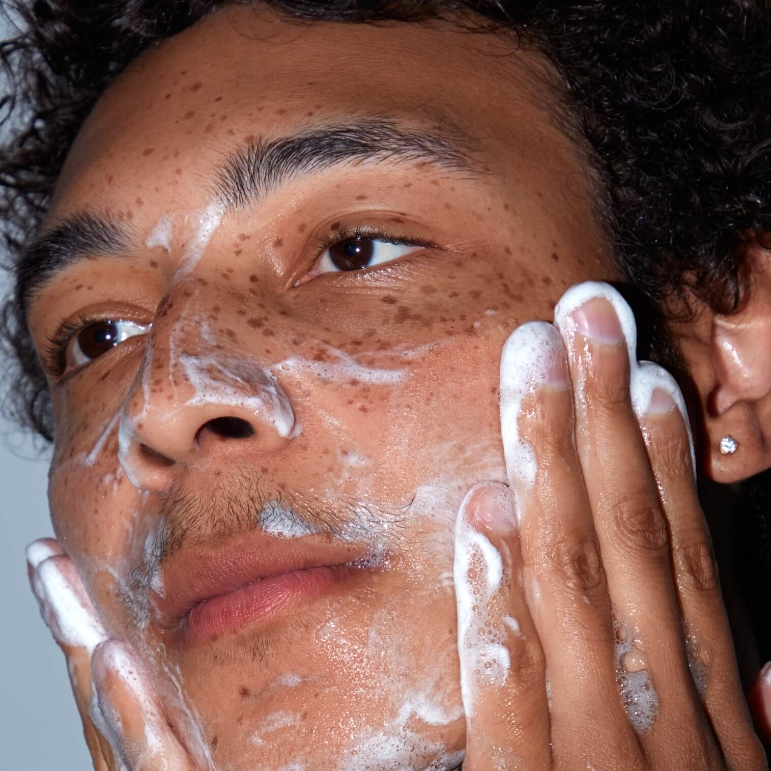 A man cleansing his face with SLMD Salicylic Acid Cleanser (step 1 of an essential skincare routine)