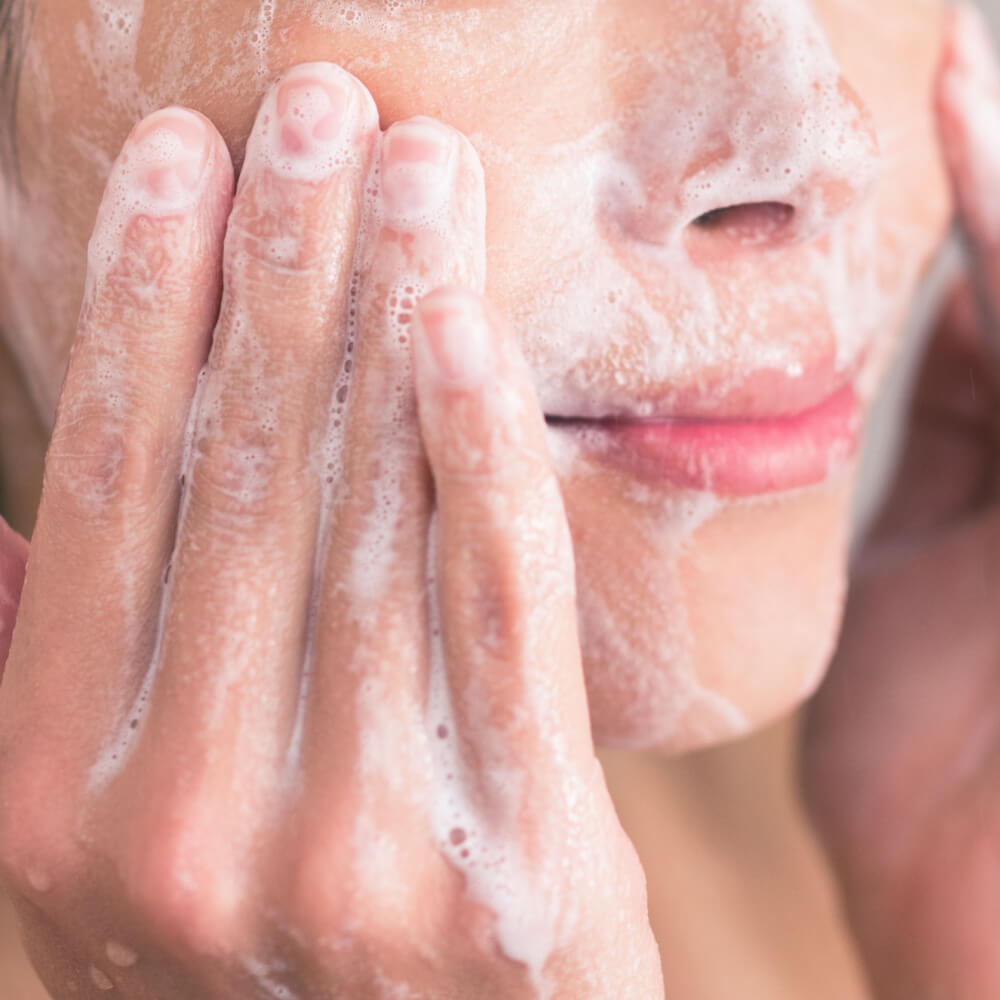 A woman washing her face with cleanser containing active ingredient salicylic acid