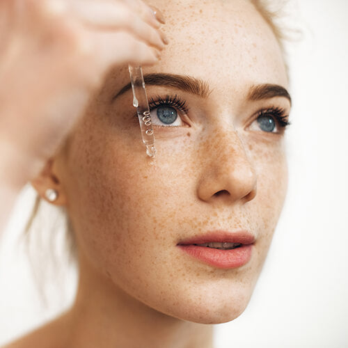 A woman using skincare serum such as amino acids