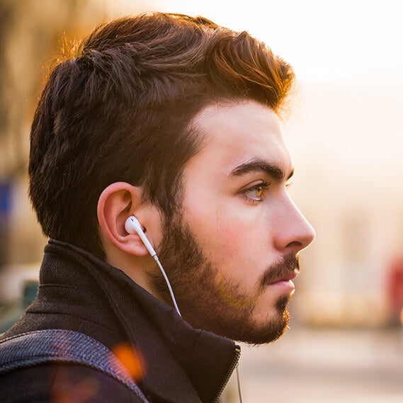 A young man wearing earbuds which can cause ear pimples