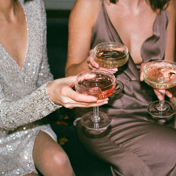 a closeup photo of women in party outfits toasting the holiday season