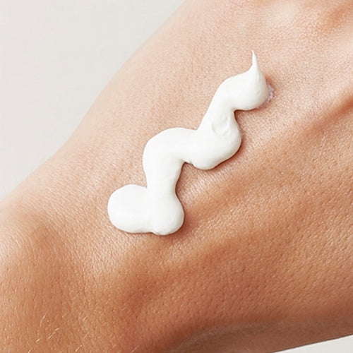 A closeup photograph of a woman's hand with sunscreen product on it