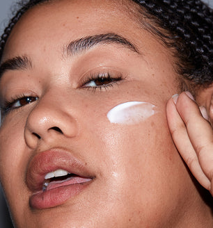 A woman applying SLMD by Dr. Pimple Popper Sulfur Lotion acne treatment